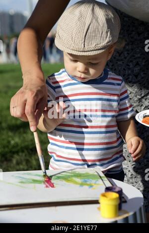Mother helping his son to paint in park Stock Photo
