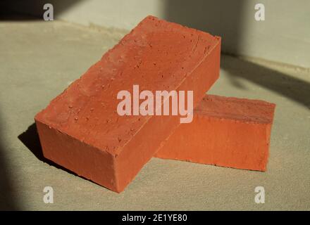 Two red bricks on a concrete floor in sunlight. Stock Photo