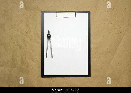 A tablet with a white sheet of A4 format with divivder on a beige craft paper. Concept of accurate measurements, study and construction. Stock photo with empty place for your text and design. Stock Photo