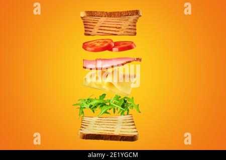 Fresh sandwich with flying ingredients on the yellow background isolated. Fly food concept Stock Photo