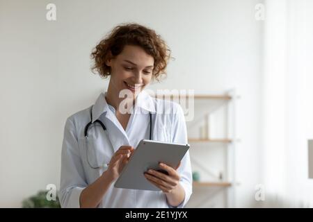Happy young professional general practitioner using digital computer tablet. Stock Photo