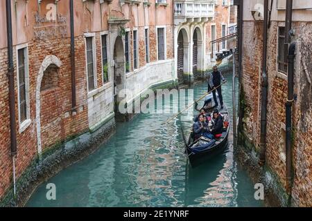 Traditional Venetian gondola with tourists on rio di Santa Maria Formosa canal in Venice, Italy Stock Photo