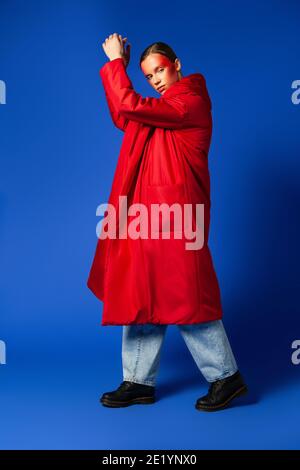 Trendy female dancing on tiptoes against blue background Stock Photo