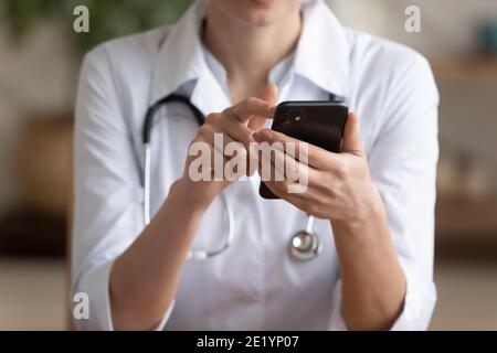 Close up young female medical worker using smartphone. Stock Photo