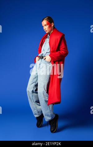 Trendy female dancing on tiptoes against blue background Stock Photo