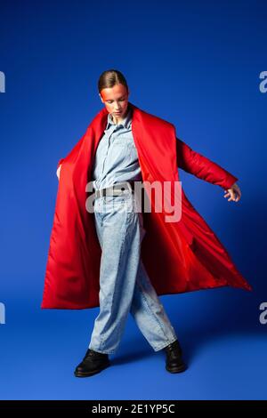 Woman in stylish coat dancing against blue background Stock Photo