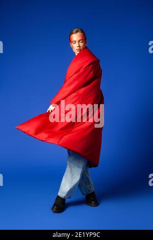 Woman in stylish coat dancing against blue background Stock Photo