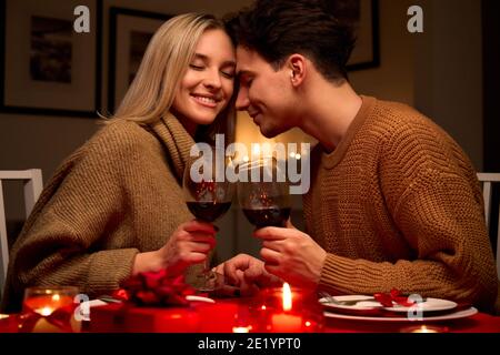 Happy couple in love clinking glasses drinking red wine having romantic dinner. Stock Photo