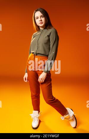 Trendy young woman looking at camera against orange background Stock Photo