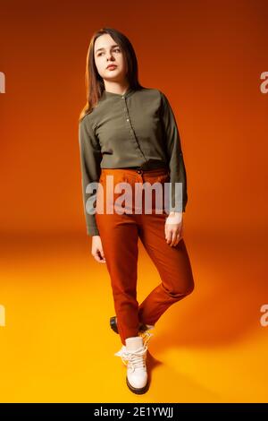 Trendy young woman looking at camera against orange background Stock Photo