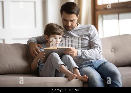 Caring father teach little son reading book Stock Photo