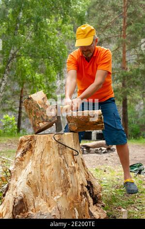 A man chops wood with an ax for a fire on a hike. Stock Photo