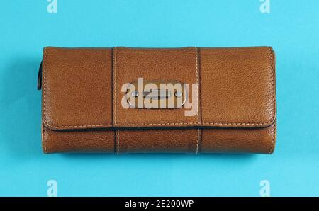 Closed expensive brown leather wallet  fashion accessory isolated on blue background Stock Photo