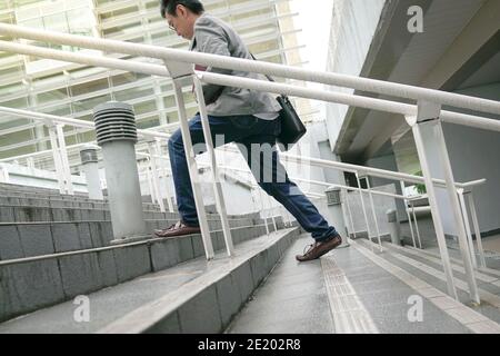 Businessman with work bag going up the stairs in a hurry, Focus on legs and feet. Climbing corporate ladder or work success concept. Stock Photo