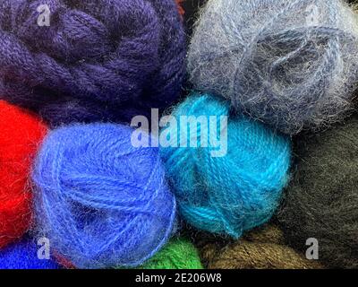 Mohair yarn in different colors, with a downy structure. Background of skeins stacked by a vertical wall. Stock Photo