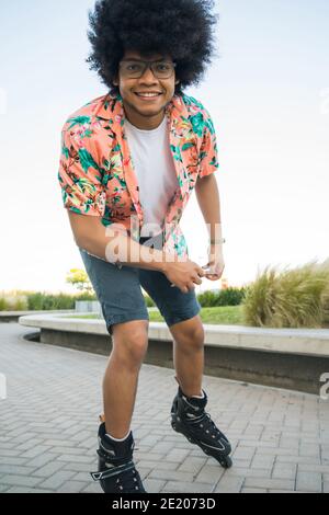 Young Latin man rollerskating outdoors. Stock Photo