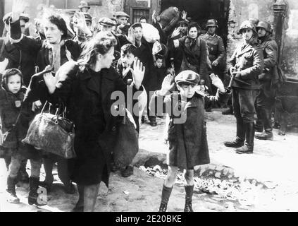 A boy raises his hands over his head as Nazi soldiers forcibly remove Polish Jews in the Warsaw Ghetto Uprising to be transported by train to Majdanek extermination camp or Treblinka. One of the most iconic photographs of WWII, the image, most likely from April or May 1943, was included in the Stoop Report given to Heinrich Himmler by SS and Police Leader Jürgen Stroop. Stock Photo