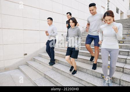 Fit young Asian men and women running down the stairs in city when training for marathon in the morning Stock Photo