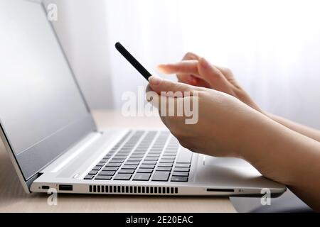 Woman using smartphone on laptop keyboard background. Concept of online communication, work and payment Stock Photo