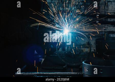 Sparks and blue glow of burning gas of welding in the dark Stock Photo