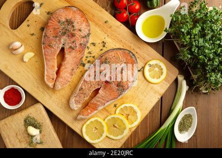 Juicy fresh salmon steak on cutting board with spices and herbs Stock Photo