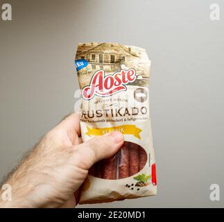 Paris, France - Dec 13, 2020: POV male hand holding package of Aoste Rustikado Klassik sausage dried Stock Photo
