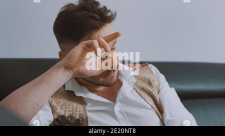 Portrait of sad depressed handsome man sitting on the couch leaning head over his hand. High quality photo Stock Photo