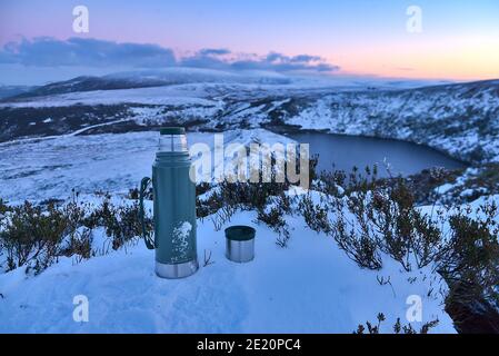 Thermos and a cup of tea at the snowy summit and scenic evening view over Lough Bray Upper lake seen from Eagles Crag, Ballylerane, Co. Wicklow, Irela Stock Photo