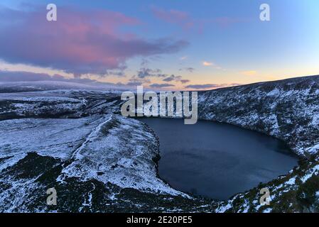 Beautiful evening view over Lough Bray Upper lake and Wicklow Mountains seen from Eagles Crag, Ballylerane, Co. Wicklow, Ireland on a frosty day. Snow Stock Photo