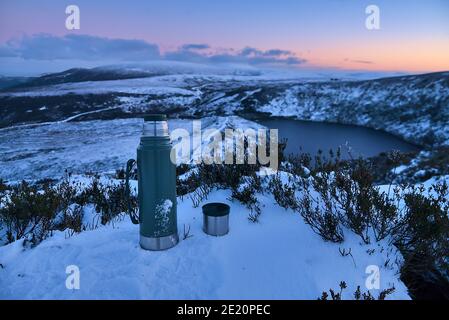 Thermos and a cup of tea at the snowy summit and scenic evening view over Lough Bray Upper lake seen from Eagles Crag, Ballylerane, Co. Wicklow, Irela Stock Photo