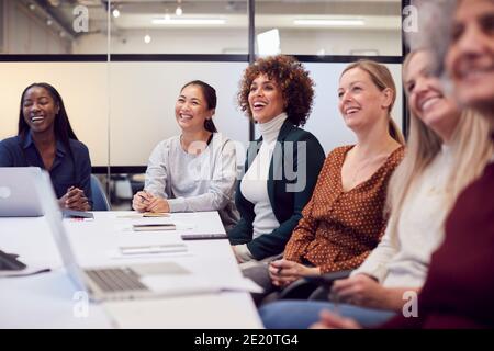 Line Of Businesswomen In Modern Office Listening To Presentation By Colleague Stock Photo