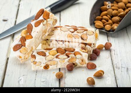 Turron blocks with almonds and hazelnuts on rustic wooden table with knife and shovel Stock Photo
