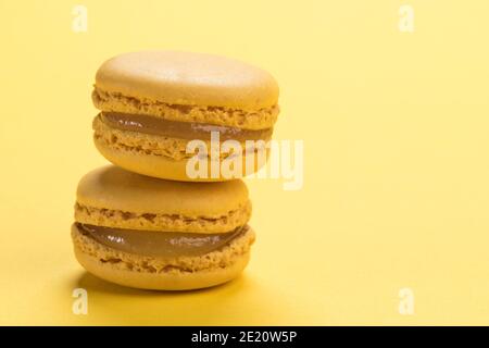 Closeup of stacked lemon flavored french macarons pastry on pastel yellow background with copy space Stock Photo