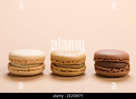 Closeup of macarons pastry filled with vanilla, coffee and chocolate sauce on light brown background Stock Photo
