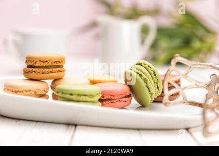 Assorted French macarons on a plate with pastry tongs on coffee table, shallow depth of field Stock Photo