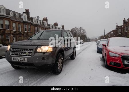 A Land Rover driving along a snow covered road in Edinburgh, Scotland UK Stock Photo