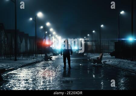 Man silhouette in misty alley at night city park, mystery and horror foggy cityscape atmosphere, alone stalker or crime person. Stock Photo