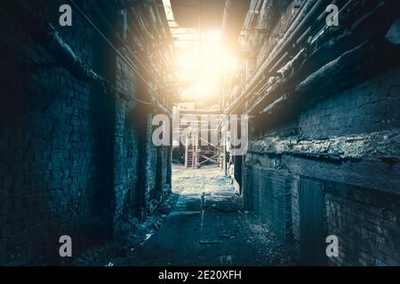 Dark dirty corridor in abandoned industrial factory with light in end, horror concept. Stock Photo