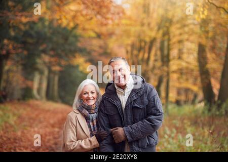 Portrait Of Loving Senior Couple Walking Along Autumn Woodland Path Through Trees Stock Photo