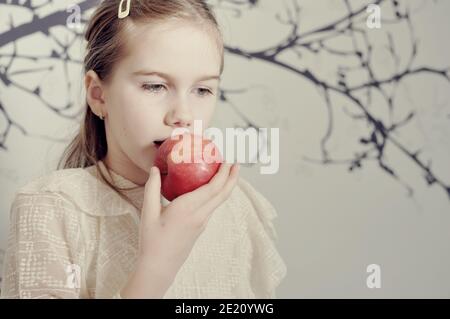 Profile portrait of an white Caucasian girl (child, kid) eating a red apple. Copy text Stock Photo