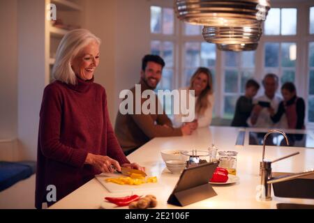 Senior Woman Preparing Meal For Family From Recipe On Digital Tablet Stock Photo