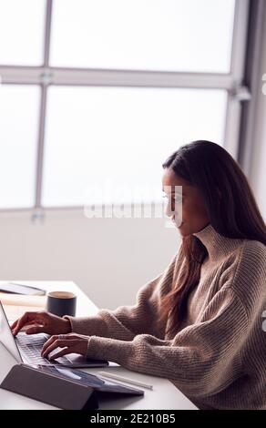Businesswoman Working On Laptop At Desk In Modern Office Stock Photo