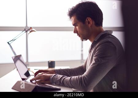 Businessman Working On Laptop At Desk In Modern Office Stock Photo