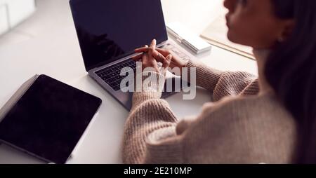 Businesswoman Sitting At Desk Using Laptop And Digital Tablet On Desk In Modern Office Stock Photo