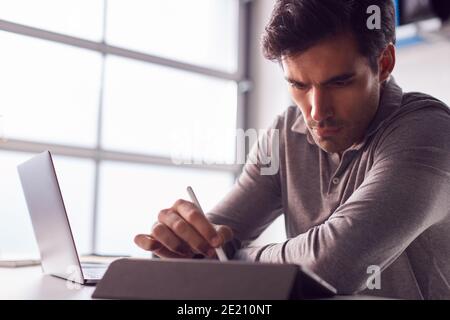 Businessman Working From Home Drawing On Digital Tablet Using Stylus Pen Stock Photo
