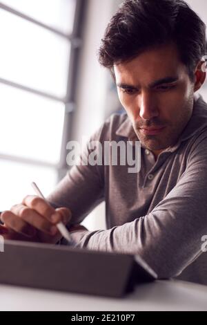 Businessman Working From Home Drawing On Digital Tablet Using Stylus Pen Stock Photo
