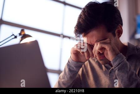 Tired Businessman Working Late Using Laptop At Desk In Office Rubbing Eyes Stock Photo
