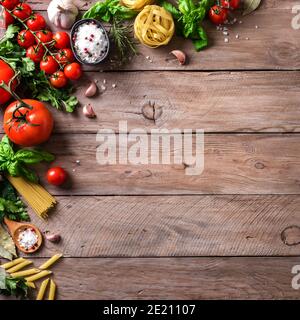 Vegetables and Uncooked pasta, cooking background, top view, copy space. Various italian pasta, tomatoes, basil herbs and spices, italian cuisine conc Stock Photo