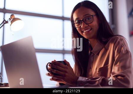 Portrait Of Businesswoman Working On Laptop At Desk In Modern Office Stock Photo