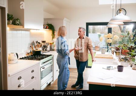 Mature Couple Having Discussion In Kitchen At Home Together Stock Photo
